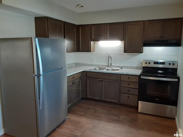 kitchen with exhaust hood, appliances with stainless steel finishes, sink, tasteful backsplash, and dark hardwood / wood-style flooring