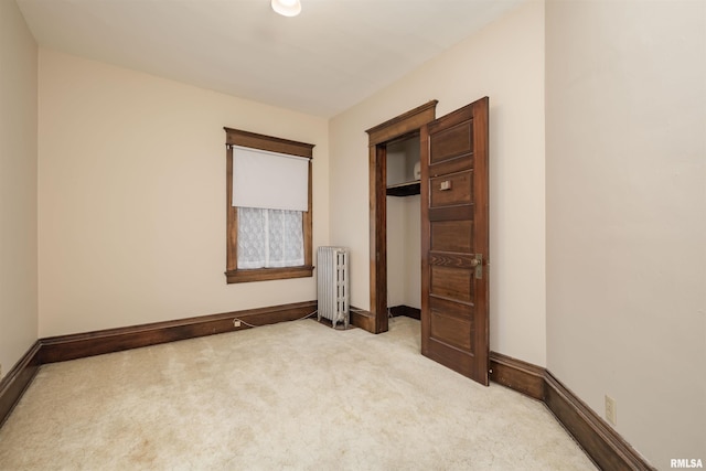 unfurnished bedroom featuring light colored carpet, a closet, and radiator