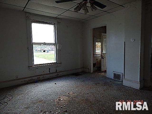 spare room with a paneled ceiling, visible vents, and ceiling fan