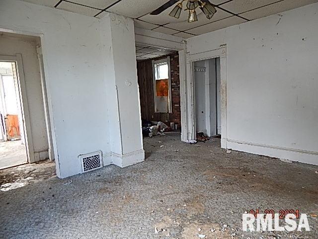 empty room with a paneled ceiling, visible vents, plenty of natural light, and ceiling fan