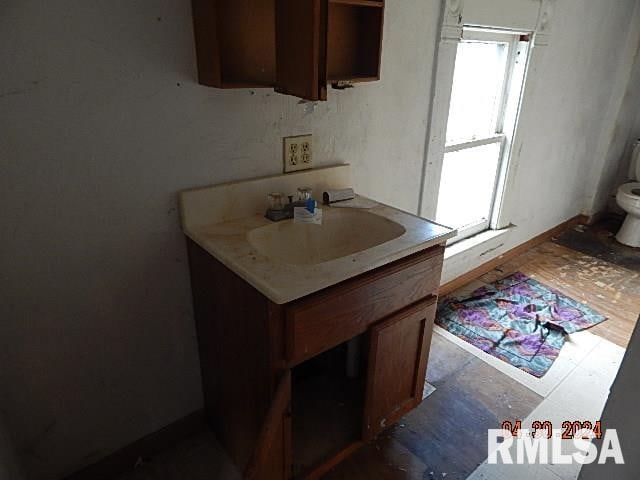 kitchen featuring brown cabinetry, light countertops, a sink, and baseboards