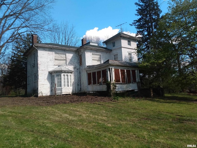 view of home's exterior with a sunroom and a yard