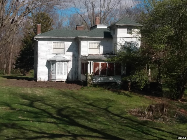 back of property with a yard and a sunroom