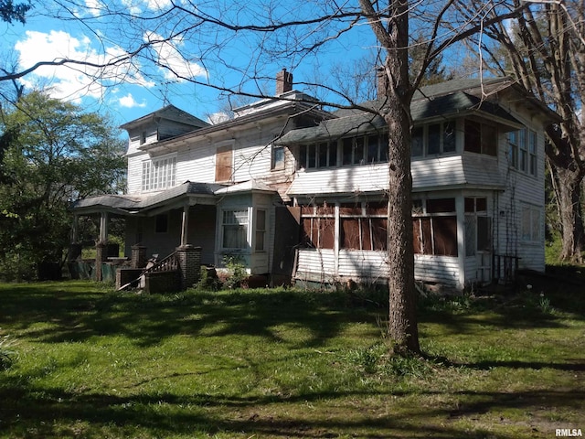 rear view of property with a yard and a sunroom