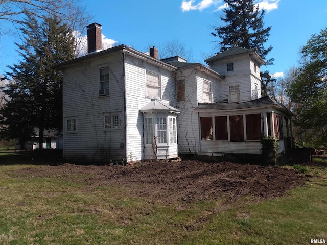 back of property with a sunroom and a yard