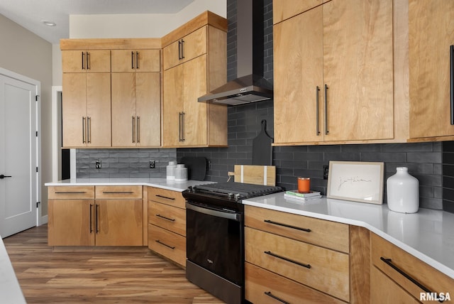 kitchen with wall chimney exhaust hood, light brown cabinets, black range with gas stovetop, and tasteful backsplash