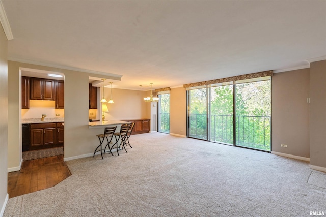 kitchen with a healthy amount of sunlight, light carpet, ornamental molding, and a chandelier