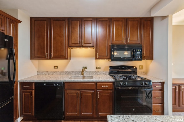 kitchen with sink, light stone counters, and black appliances