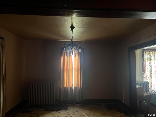 unfurnished room with an inviting chandelier and radiator