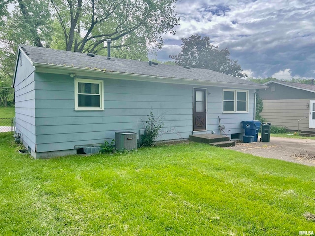 rear view of house with a lawn and cooling unit