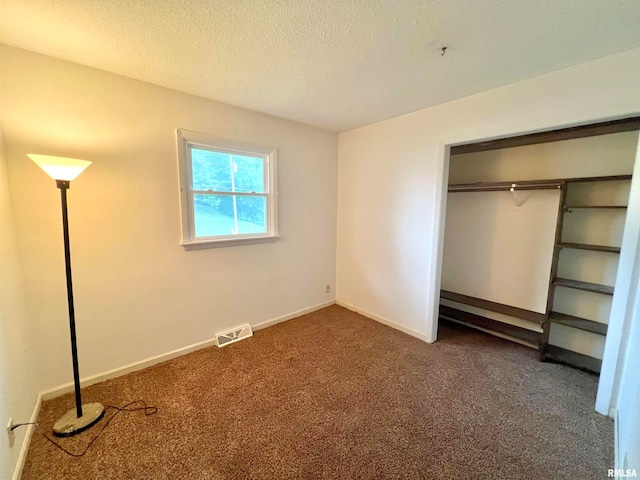 unfurnished bedroom with a closet, dark colored carpet, and a textured ceiling