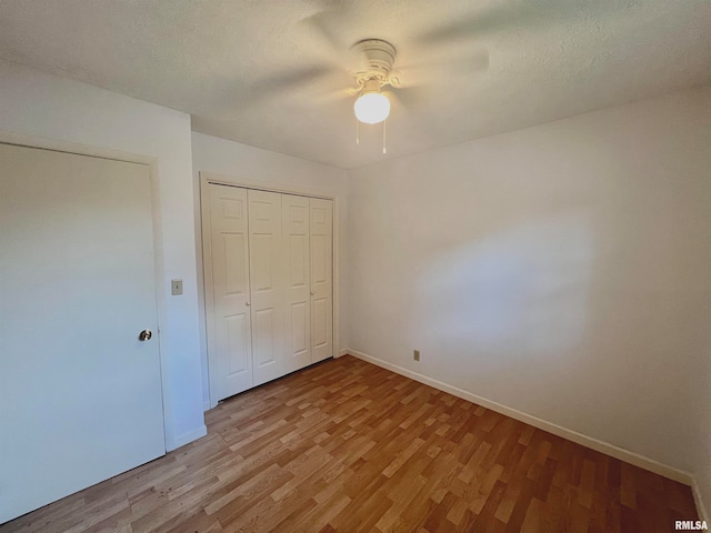 unfurnished bedroom featuring a textured ceiling, a closet, wood-type flooring, and ceiling fan