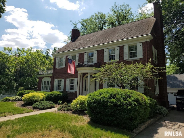 georgian-style home featuring a chimney and brick siding