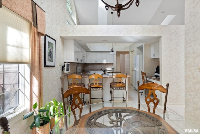 dining space with light tile patterned floors and high vaulted ceiling