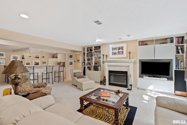 carpeted living room with a tiled fireplace and built in shelves