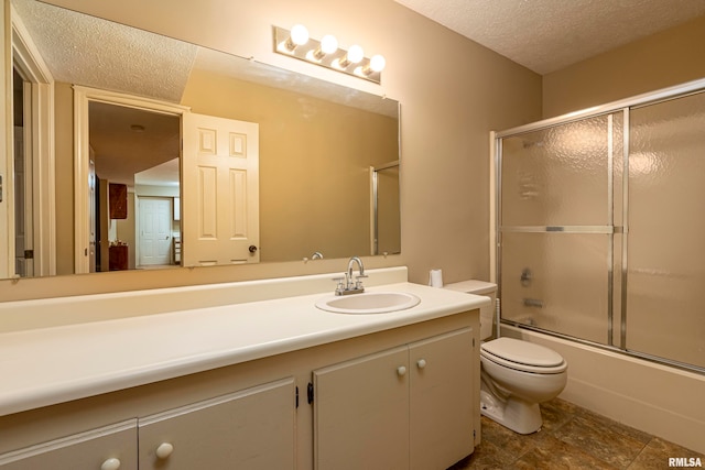 full bathroom with a textured ceiling, shower / bath combination with glass door, vanity, and toilet