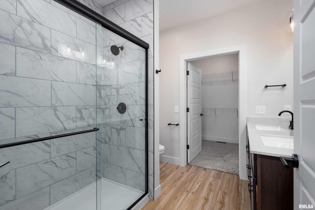 bathroom featuring vanity, hardwood / wood-style flooring, toilet, and a shower with shower door