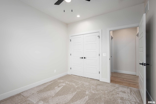 unfurnished bedroom featuring light carpet, a closet, and ceiling fan