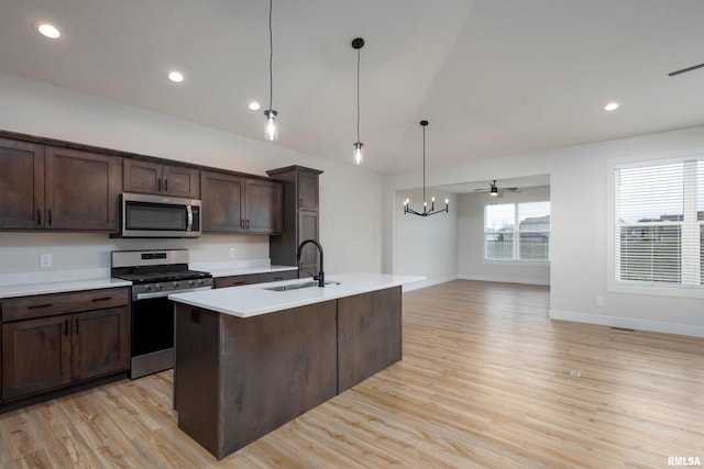 kitchen featuring dark brown cabinets, stainless steel appliances, sink, decorative light fixtures, and light hardwood / wood-style floors