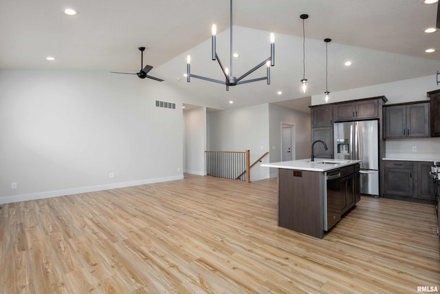 kitchen with a kitchen island with sink, stainless steel appliances, vaulted ceiling, and light hardwood / wood-style floors