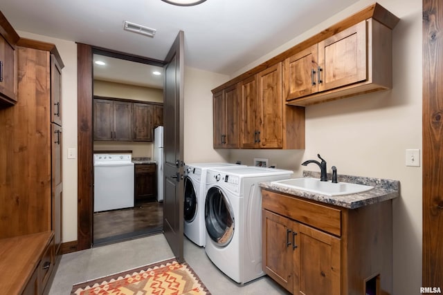 clothes washing area featuring cabinet space, a sink, visible vents, and separate washer and dryer