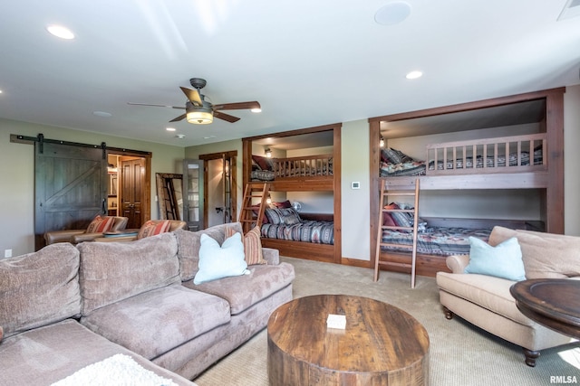 carpeted living room with a barn door and ceiling fan