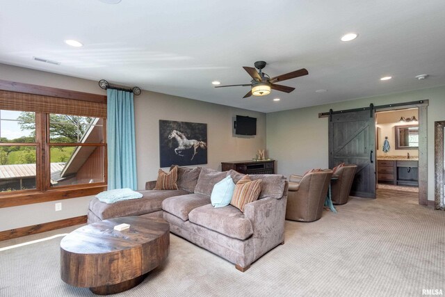 living room with a barn door, carpet, and ceiling fan