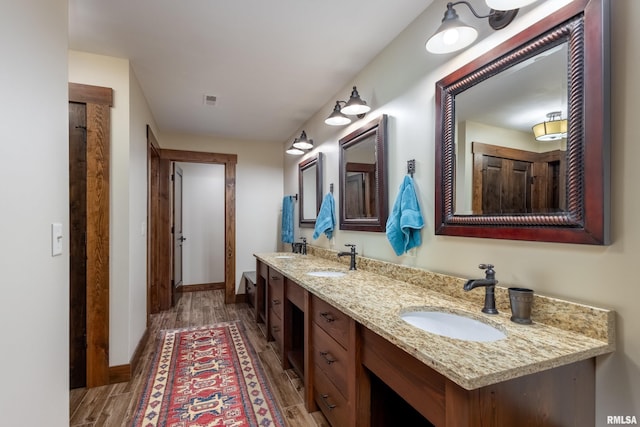 bathroom with double vanity, a sink, and wood finished floors