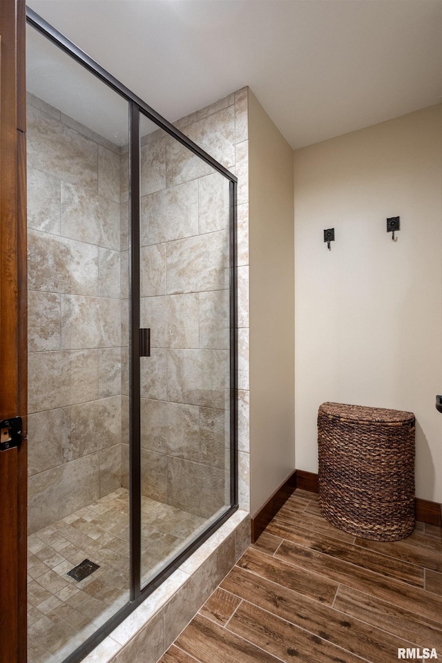 bathroom featuring a shower stall, baseboards, and wood finished floors