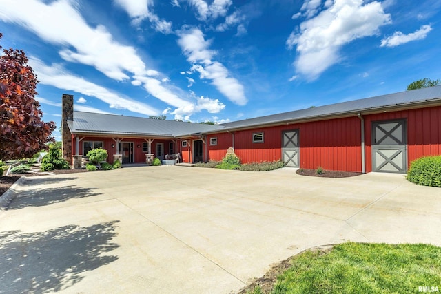 view of front of property featuring an outbuilding, metal roof, board and batten siding, and a chimney