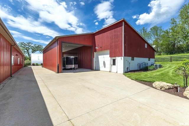 view of outdoor structure featuring central air condition unit, a garage, a carport, and a lawn