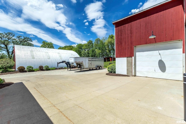 exterior space with concrete driveway, an outdoor structure, and a detached garage