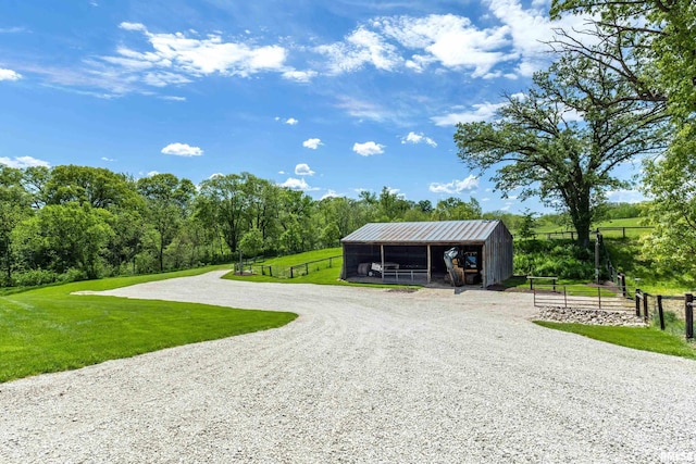 exterior space featuring an outbuilding, driveway, a carport, and a lawn