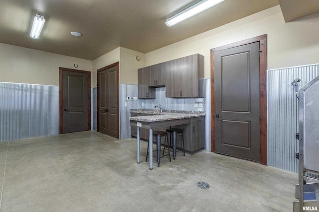 kitchen featuring dark brown cabinetry, sink, tasteful backsplash, and a breakfast bar