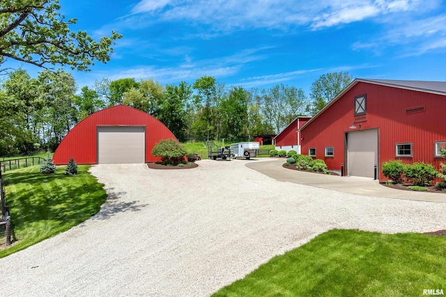 exterior space featuring an outbuilding, gravel driveway, fence, a garage, and a pole building