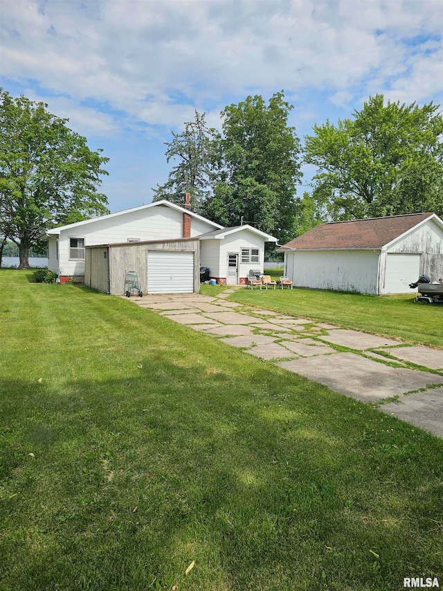 exterior space featuring a garage, a lawn, and an outbuilding