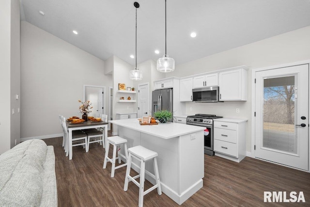 kitchen featuring pendant lighting, a breakfast bar area, white cabinetry, stainless steel appliances, and a center island