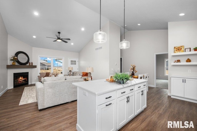 kitchen with decorative light fixtures, dark wood-type flooring, white cabinets, and a kitchen island