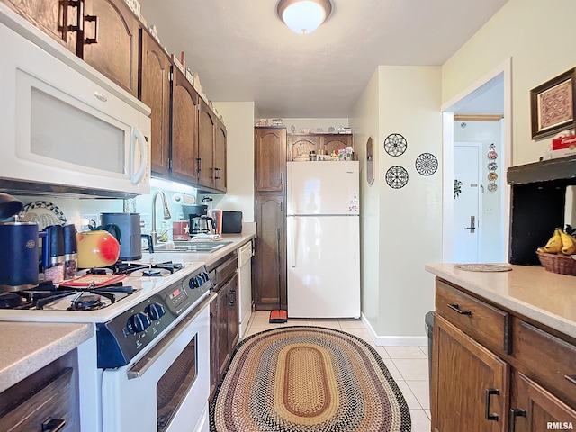 kitchen featuring sink, light tile patterned floors, and white appliances