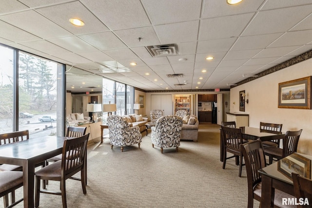 carpeted dining space featuring a paneled ceiling and plenty of natural light