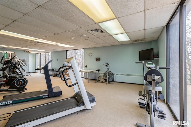 exercise room with radiator, carpet, and a drop ceiling