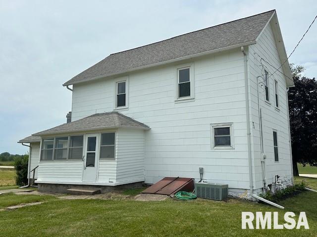 back of property with central AC unit and a lawn