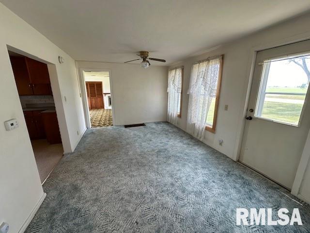 unfurnished living room featuring carpet flooring and ceiling fan