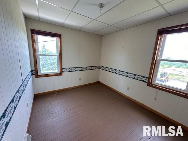 empty room with hardwood / wood-style flooring and a drop ceiling