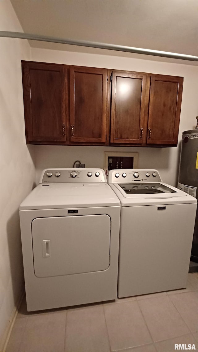 laundry room with water heater, light tile patterned floors, cabinets, and independent washer and dryer