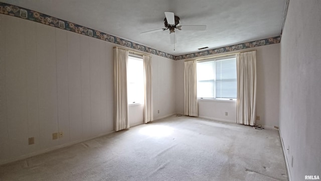 carpeted empty room featuring ceiling fan and a healthy amount of sunlight