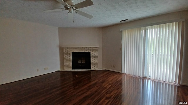 unfurnished living room featuring a fireplace, a textured ceiling, a wealth of natural light, and dark wood-type flooring