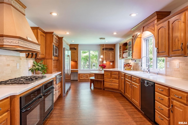 kitchen featuring sink, custom exhaust hood, decorative light fixtures, dark hardwood / wood-style floors, and black appliances