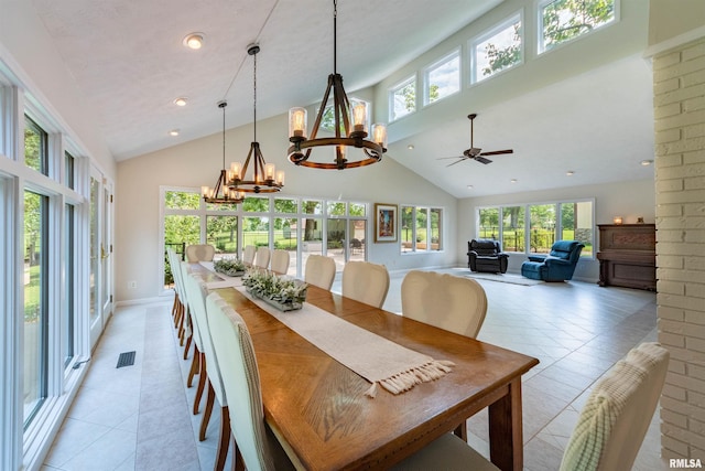 dining room with ceiling fan with notable chandelier, light tile patterned floors, and high vaulted ceiling