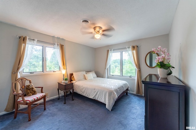 bedroom featuring ceiling fan, dark carpet, and a textured ceiling